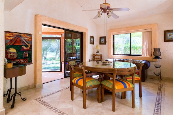 A dining area with a round table, wooden chairs, and a ceiling fan.