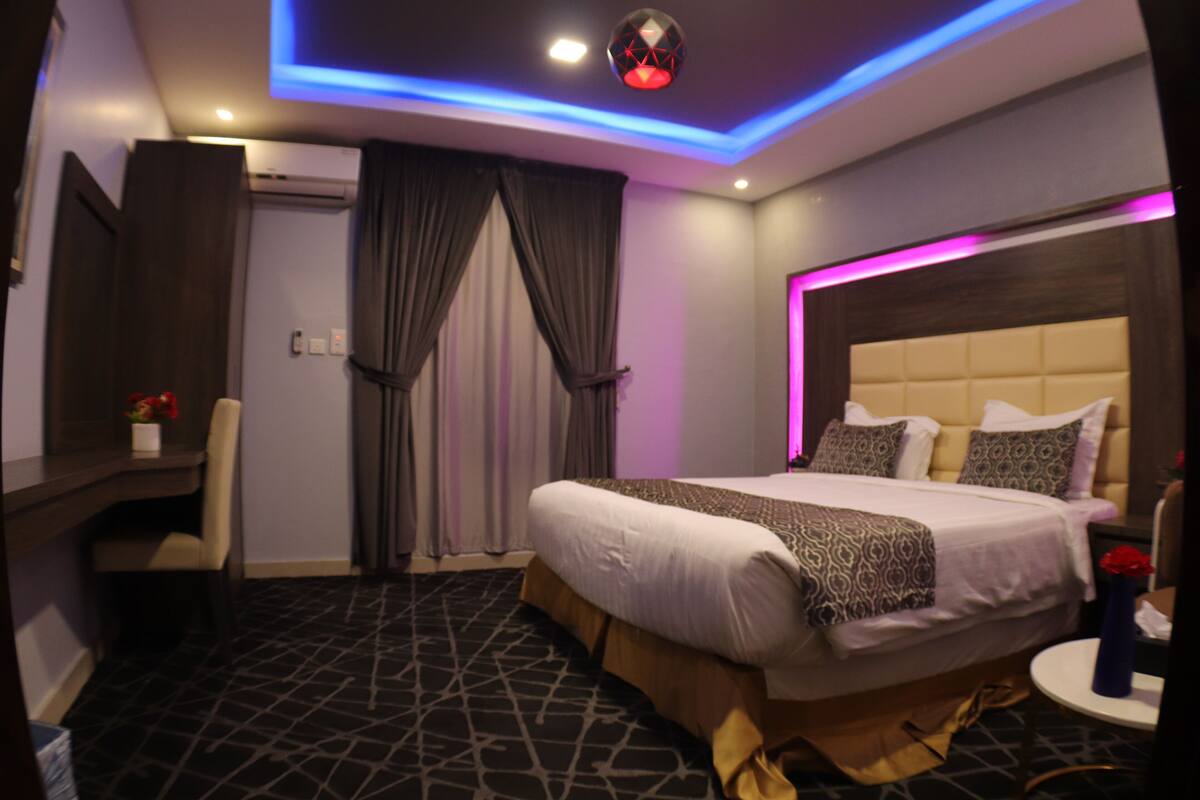 Una habitación de hotel moderna con una cama grande, un escritorio y una silla.