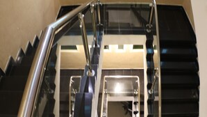 Una escalera con cerramiento de vidrio, barandales de metal y pasamanos.