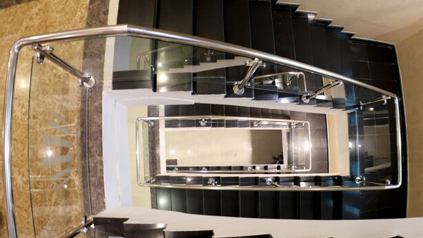 Una escalera moderna con barandillas de vidrio y peldaños negros.