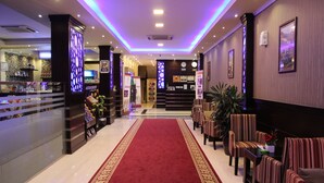 A hotel lobby with a red carpet, seating area, reception desk, and decorative wall panels. - Maskan Al Dyafah Serviced Apartments 2 (Dammam)