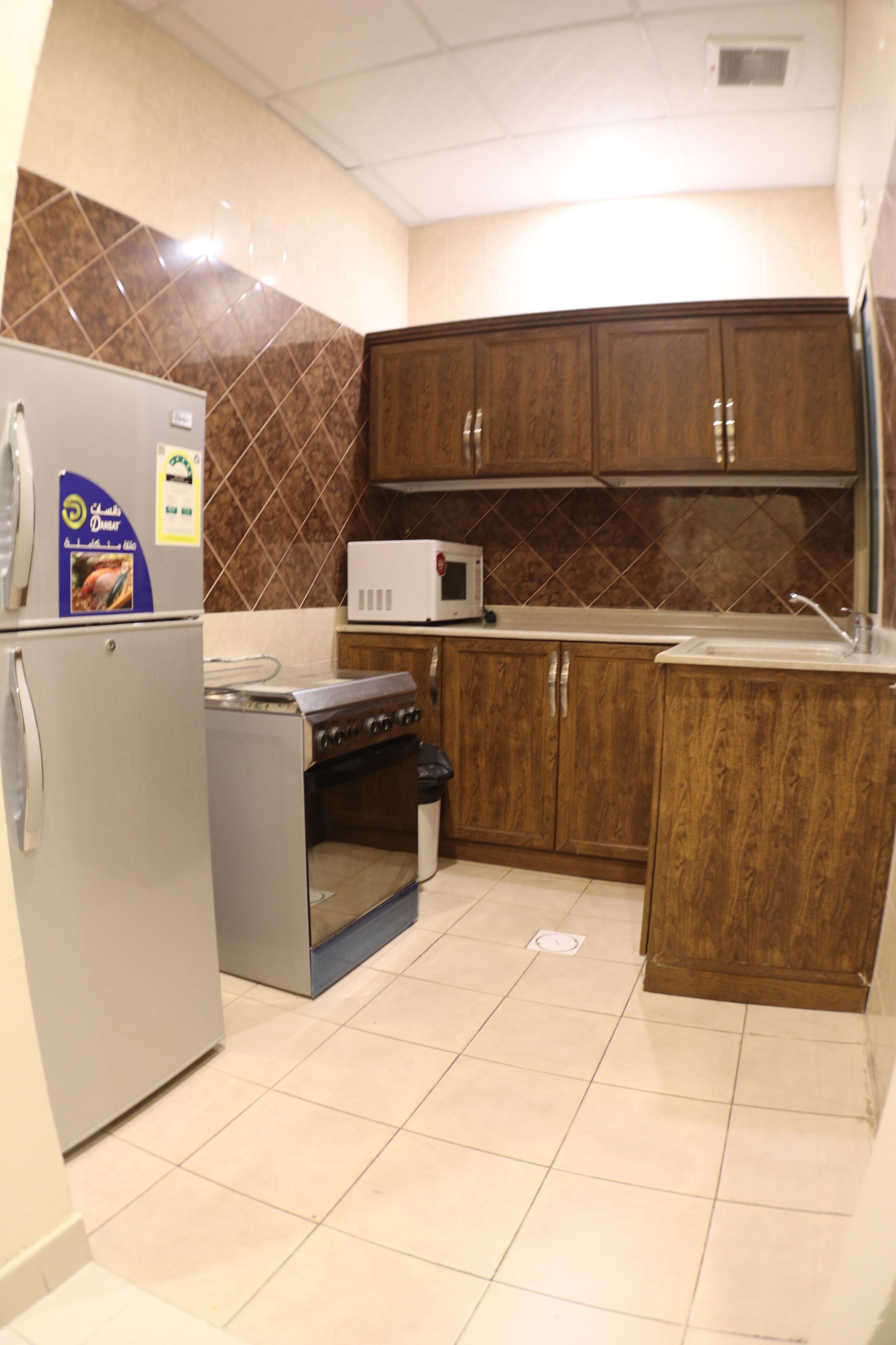 Una cocina con refrigerador, estufa, microondas y gabinetes de madera.