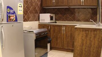 Una cocina con refrigerador, estufa, microondas y gabinetes de madera.