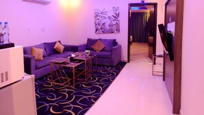 A modern living room with a purple sofa, a coffee table, and a flat-screen TV. - Maskan Al Dyafah Serviced Apartments 2 (Dammam)