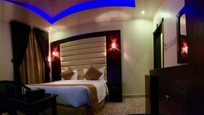 A hotel room with a curved ceiling, a bed with multiple pillows, a TV, a desk, and a dresser. - Maskan Al Dyafah Serviced Apartments 2 (Dammam)