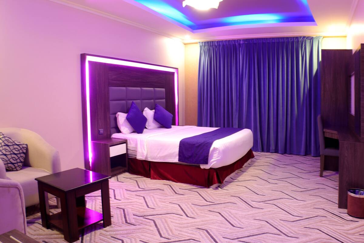 Una habitación de hotel con una cama grande, una mesita de noche, una pequeña mesa y una silla.
