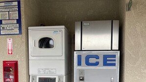 A laundromat with stacked washers and dryers, a fire extinguisher, and an ice machine. - Arlington Inn (Riverside)