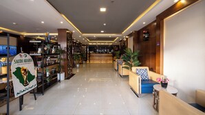 Um saguão de hotel com balcão de recepção, áreas de estar e um grande letreiro indicando a participação da Arábia Saudita na Copa do Mundo FIFA de 2022.
