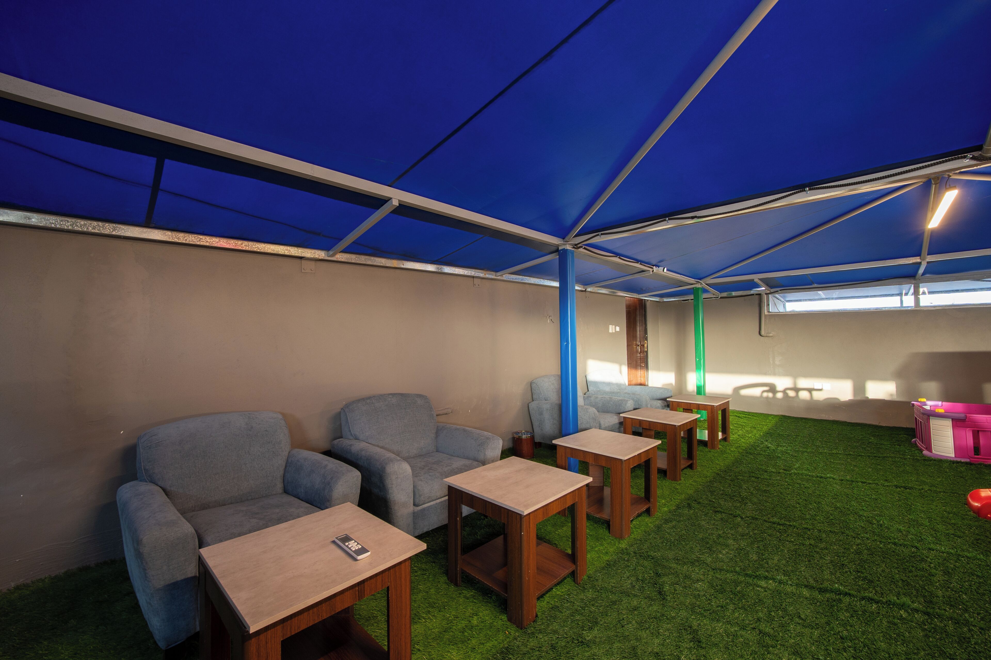 Una habitación con techo azul, césped artificial verde y sofás grises.