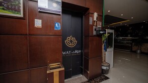 Entrada de hotel com balcão de recepção, um quadro emoldurado e um aviso indicando um prêmio de avaliação de hóspedes.