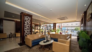 Um hall moderno com um sofá, cadeiras, uma mesa de centro e uma planta decorativa.