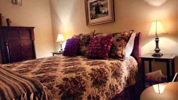 A neatly made bed with floral bedding, a framed picture on the wall, and two bedside lamps.