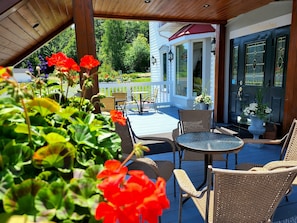 Un patio techado con mobiliario de mimbre, una puerta de cristal y vistas a un jardín exuberante.