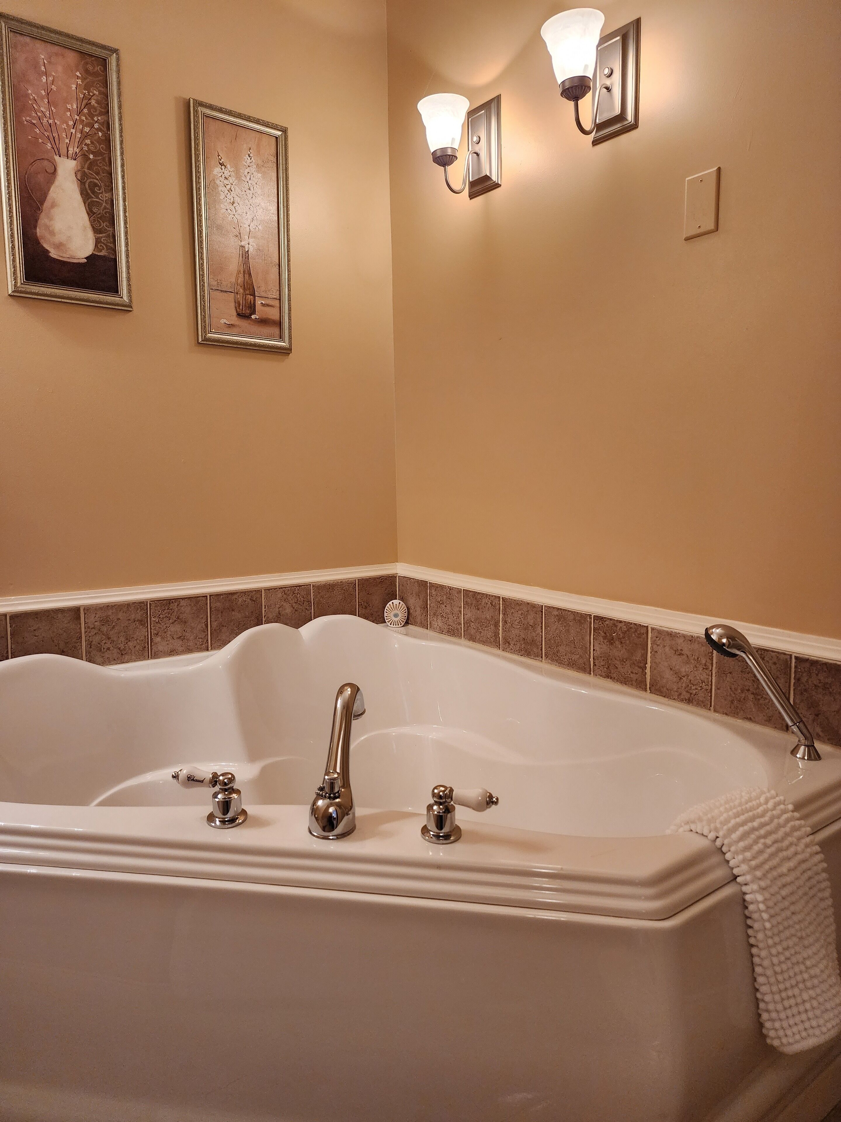 Une salle de bain avec une baignoire sur pieds, deux appliques murales et deux œuvres d’art encadrées accrochées au mur.