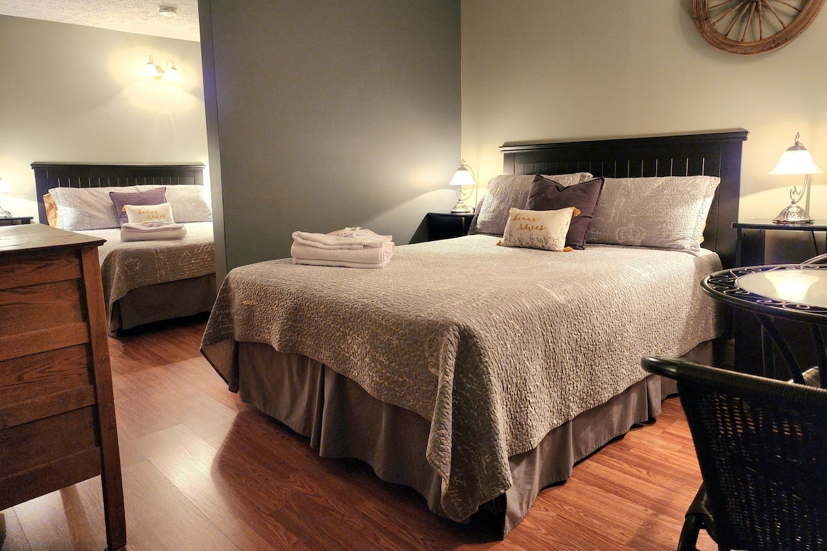 Une chambre d’hôtel avec un grand lit, deux tables de chevet, une chaise et une commode en bois.