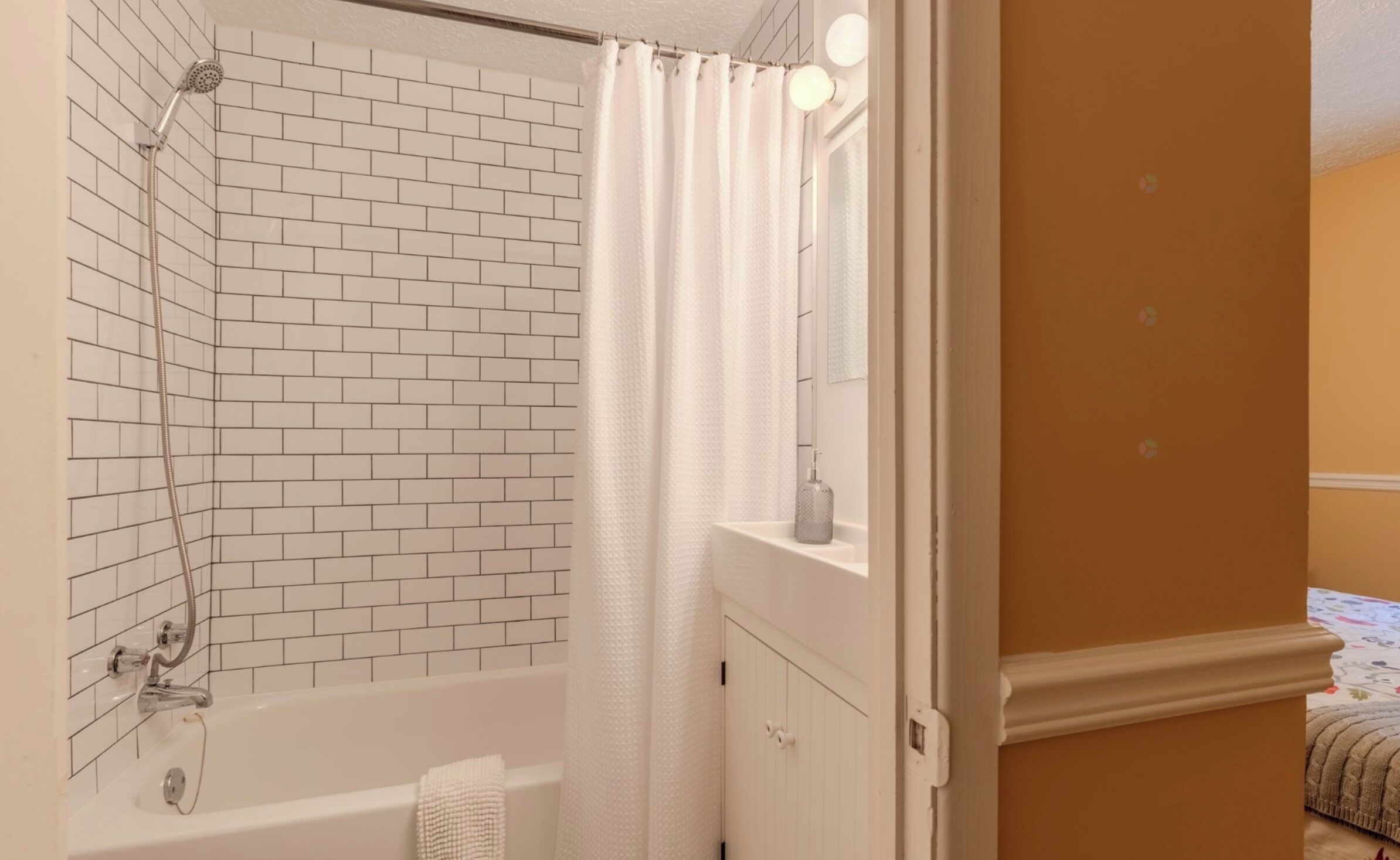 Une salle de bain avec une douche, une baignoire, une serviette blanche et un miroir.