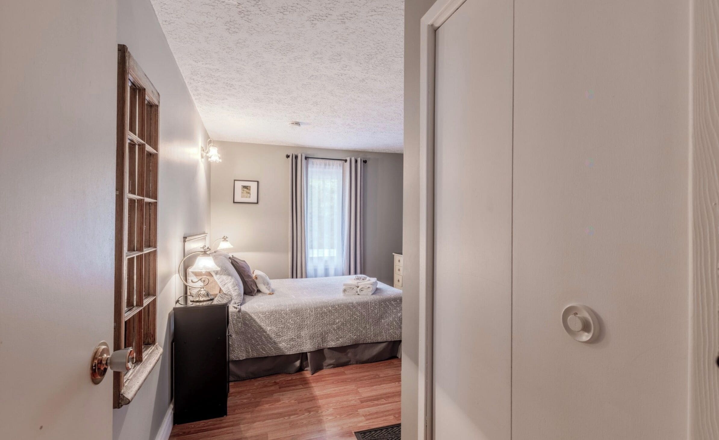 A bedroom with a bed, bedside lamps, a door, and a window with curtains.