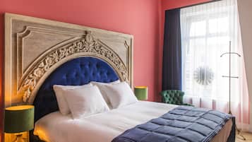 A bedroom with a large bed, a decorative headboard, a green chair, and a floor lamp.