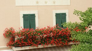 Facciata di un edificio con la scritta 'ALBERGO LIVORNO' e tre stelle. Si notano due finestre con persiane verdi e un balcone con fiori rossi.