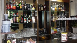 Un'area bar con scaffali pieni di bottiglie di liquori, bicchieri e una macchina per il caffè.