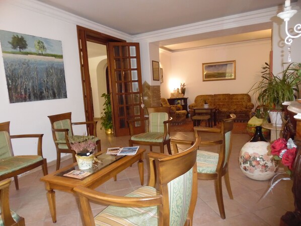 A living room with a dining table, chairs, a sofa, and a fireplace. - Albergo Livorno (Casciana Terme Lari)