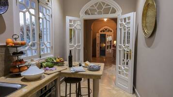Una cocina con una isla grande, un comedor con un arco alto y vistas al jardín a través de las ventanas.