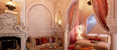 A luxurious room with ornate decor, a fireplace, a sofa, and a bed with a canopy.