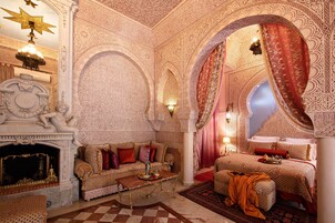 Una habitación lujosa con decoración ornamentada, una chimenea, un sofá y una cama con dosel.