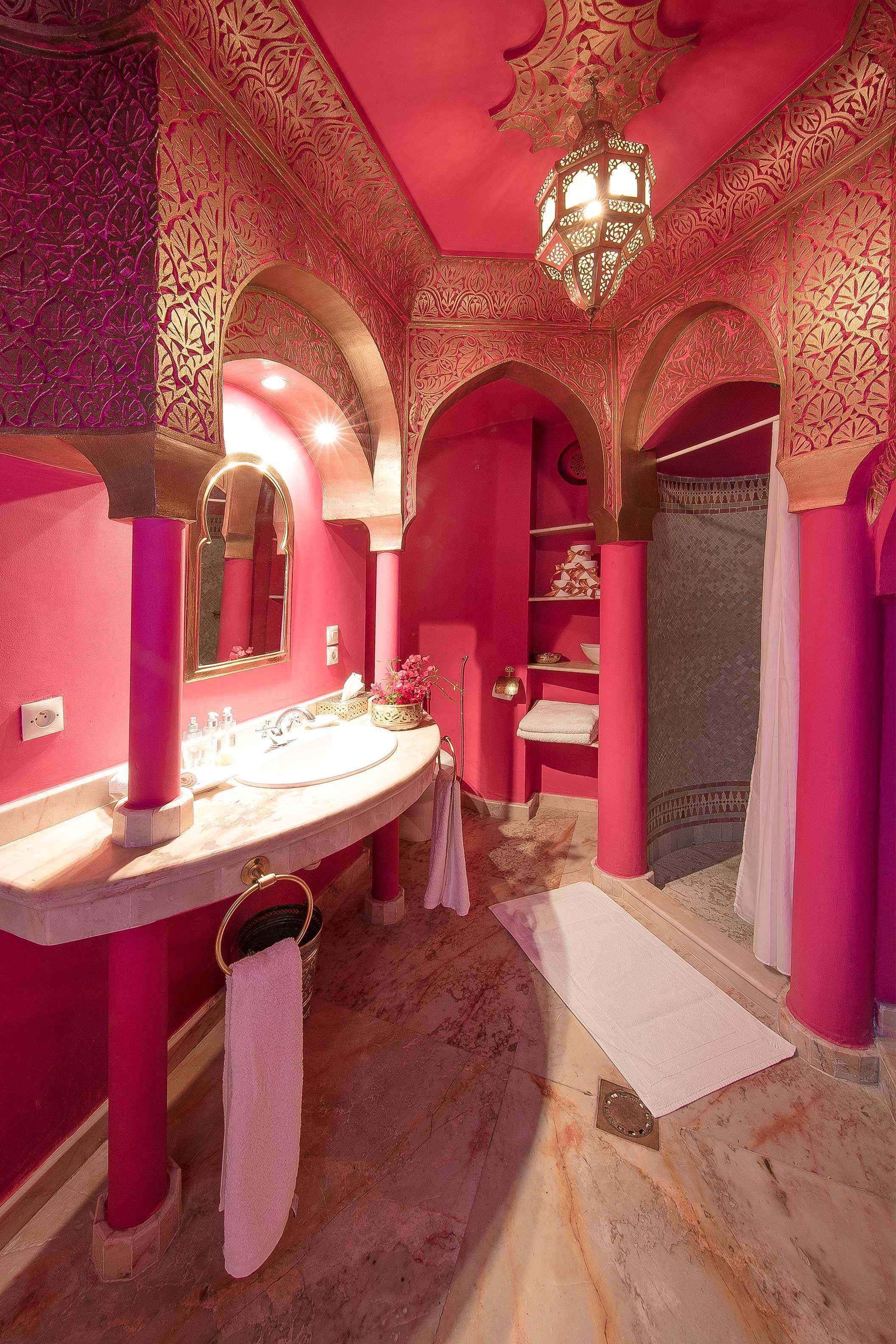 Un baño con decoración rosa, un espejo grande, un lavamanos y una zona de ducha.