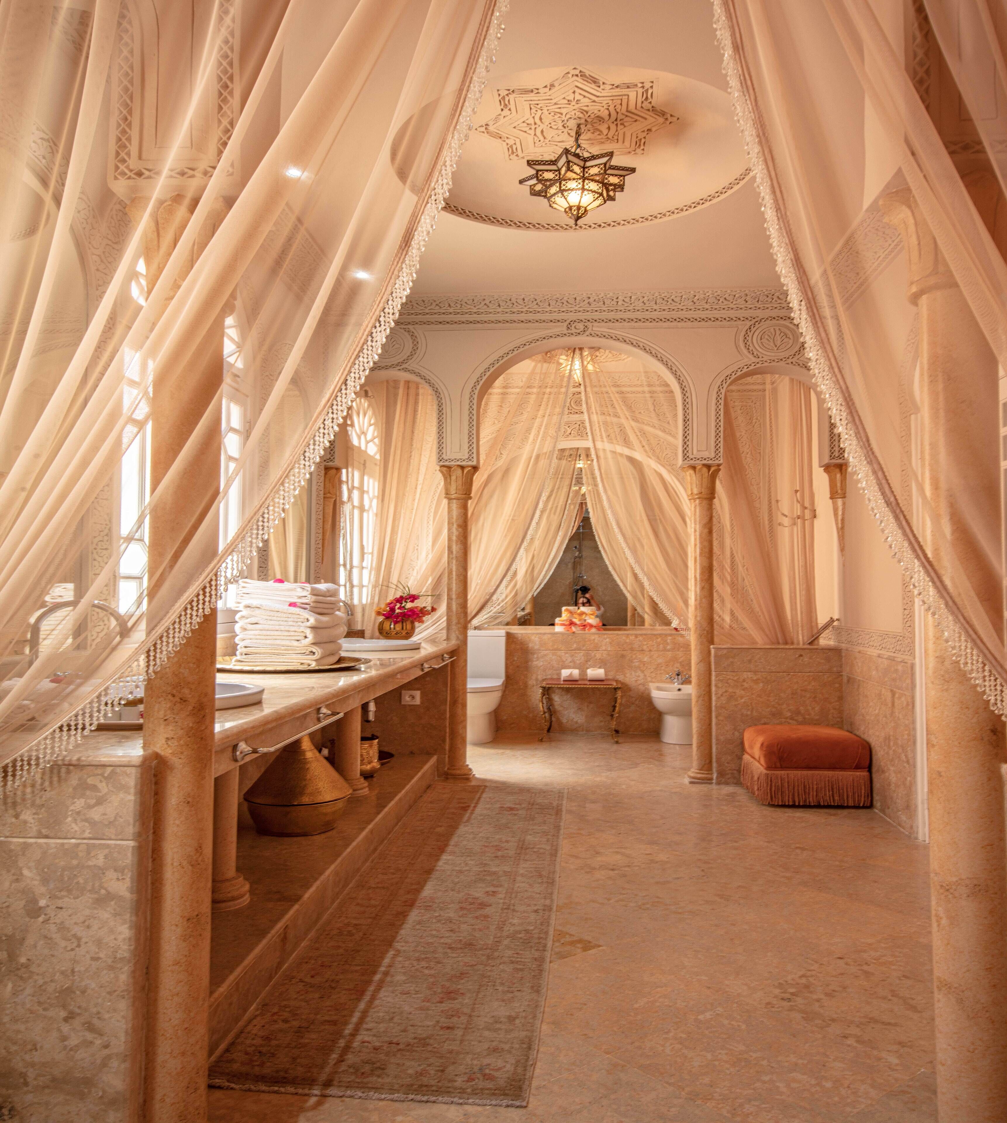 A luxurious bathroom with ornate arches, a vanity with a mirror, and a hanging light fixture.