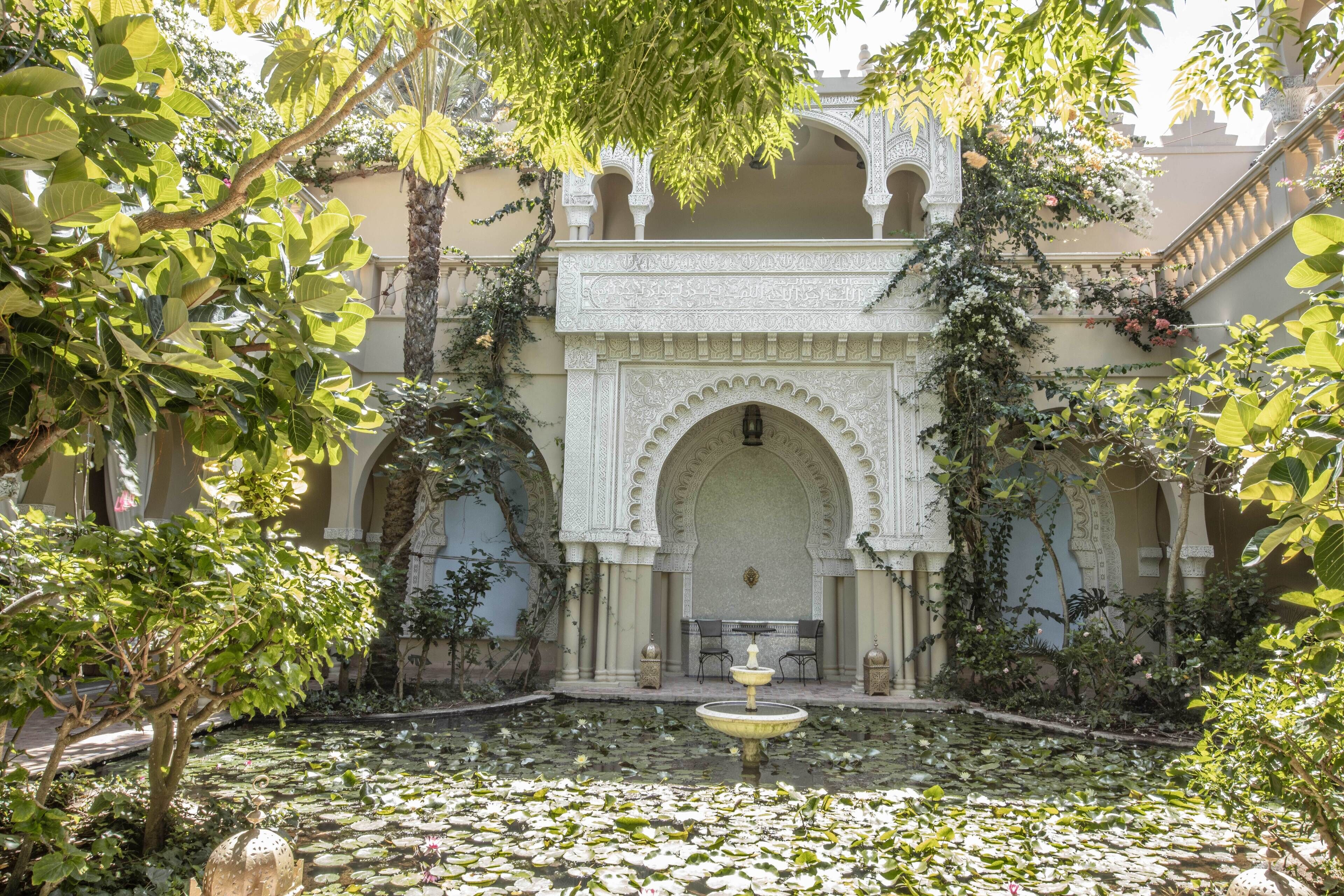 A courtyard with a fountain, arches, and lush greenery.