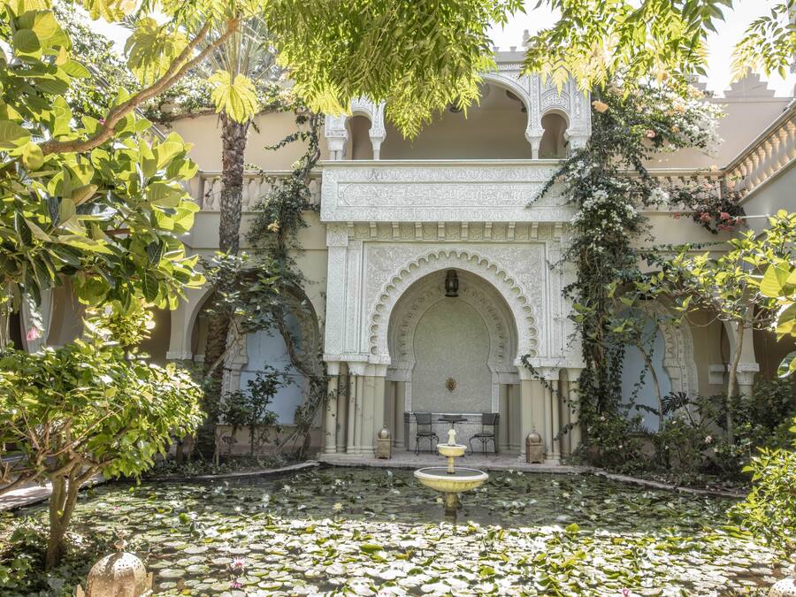 A courtyard with a fountain, arches, and lush greenery.