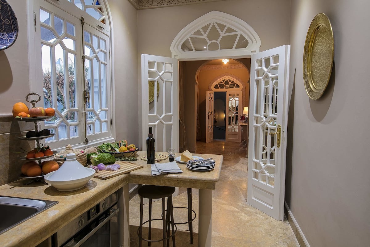 A kitchen with a large white bowl, a wine bottle, and a fruit bowl on the counter.