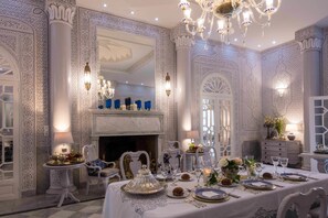 Un comedor lujoso con paredes blancas ornamentadas, una chimenea y un candelabro.
