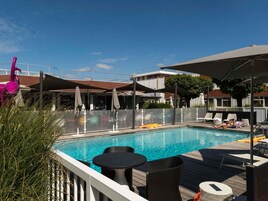 Una piscina al aire libre, sillones reclinables de piscina