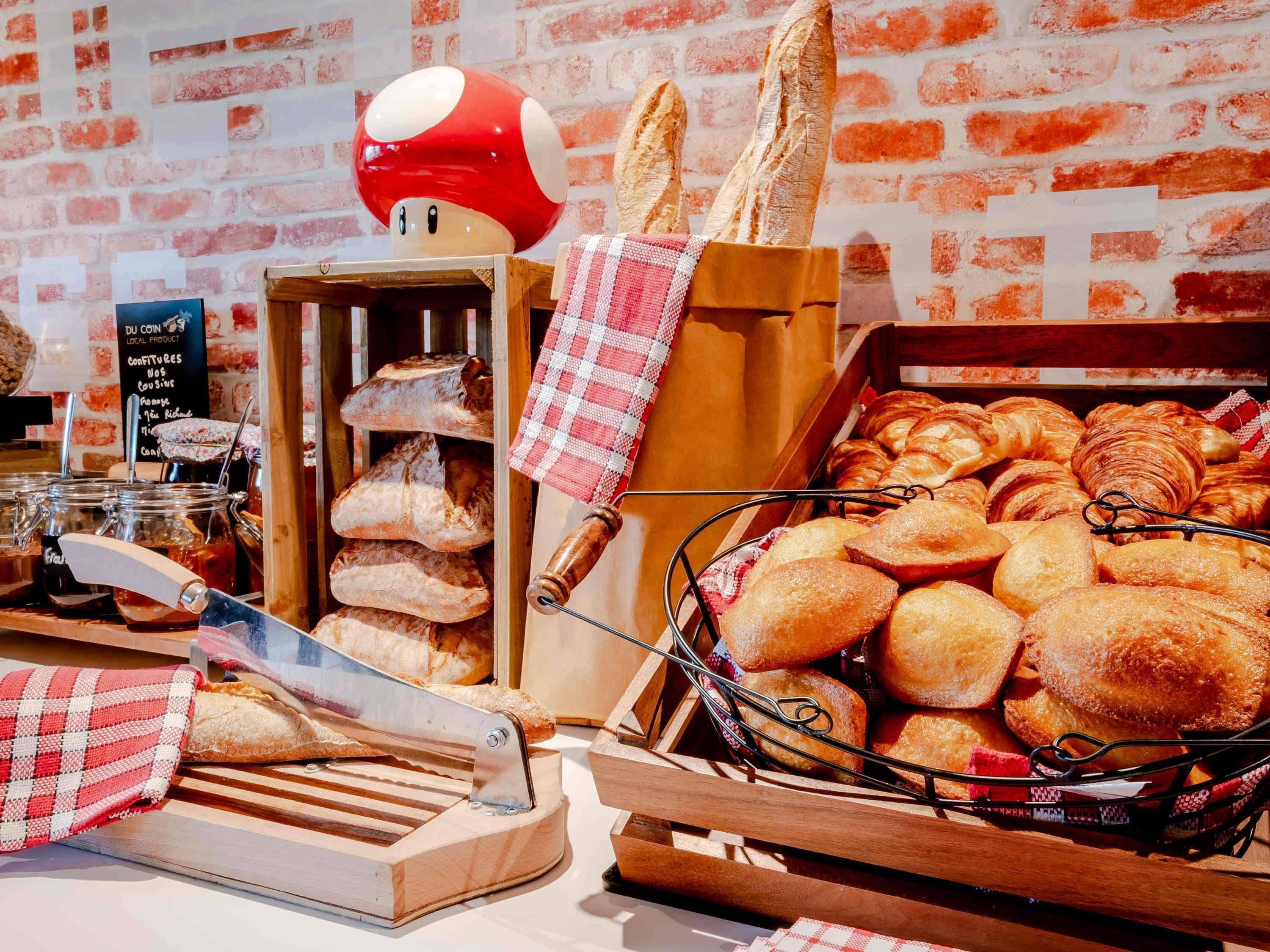 A bakery display with various breads and pastries, a knife, and a red mushroom decoration.