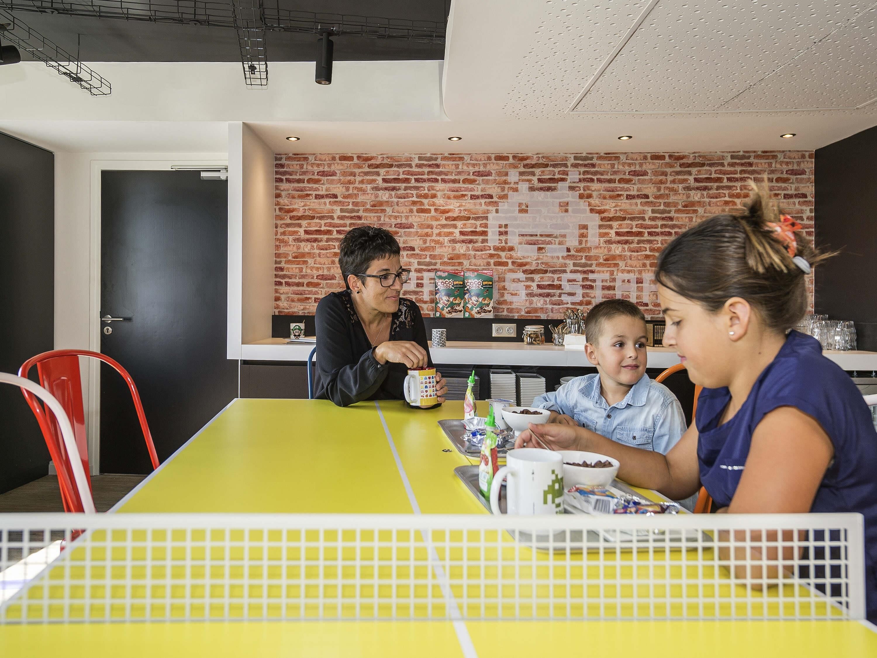 A dining area with a yellow table, a brick wall, and a door in the background.
