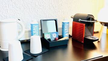 A coffee station with a coffee machine, cups, and a water bottle.