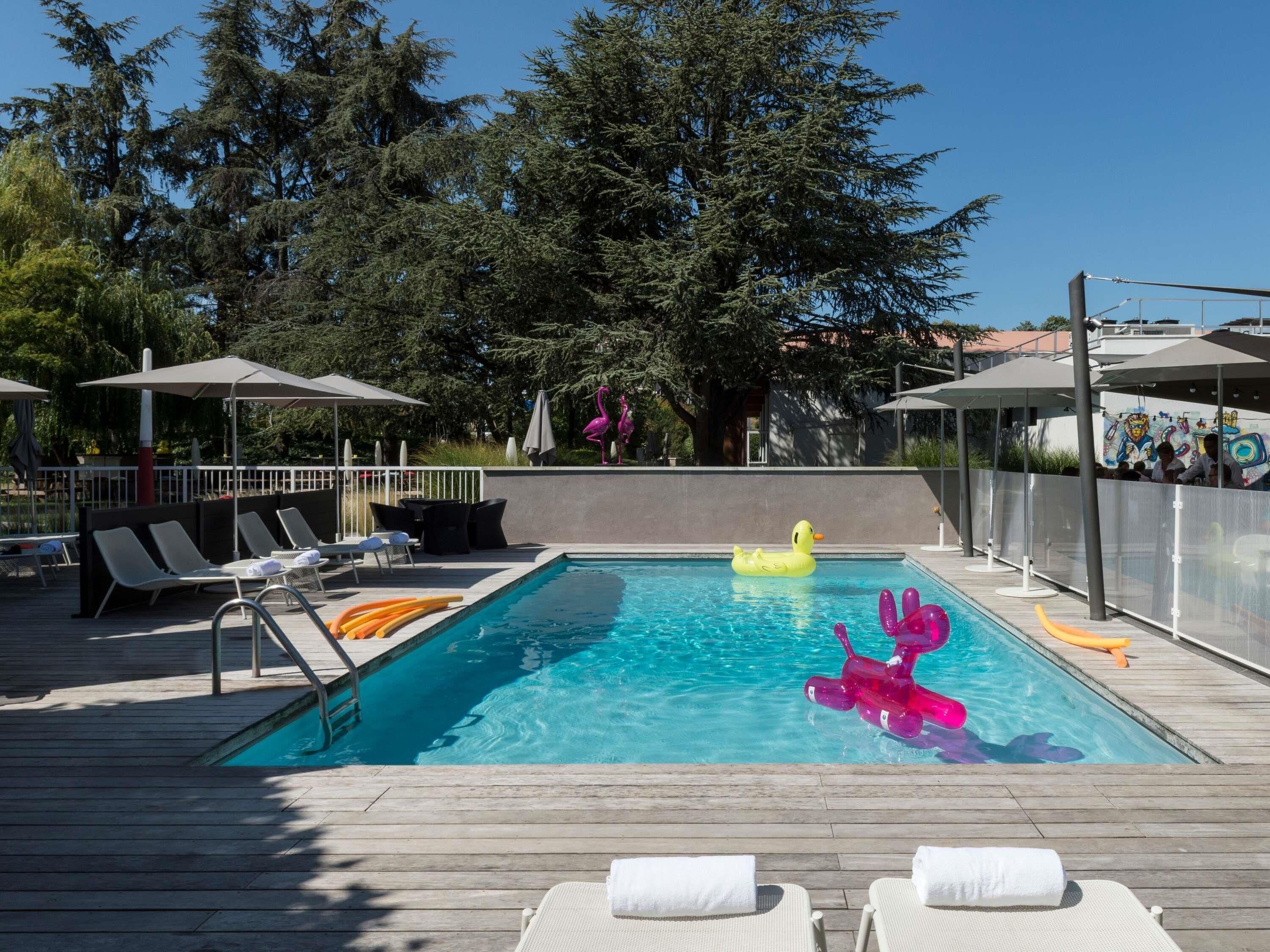 A swimming pool with lounge chairs, a wooden deck, and a fence.