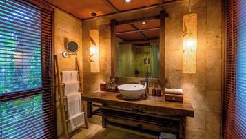 Une salle de bain avec un grand lavabo, un meuble-lavabo en bois et un miroir. Des serviettes sont suspendues sur un porte-serviettes et il y a un sèche-serviettes.