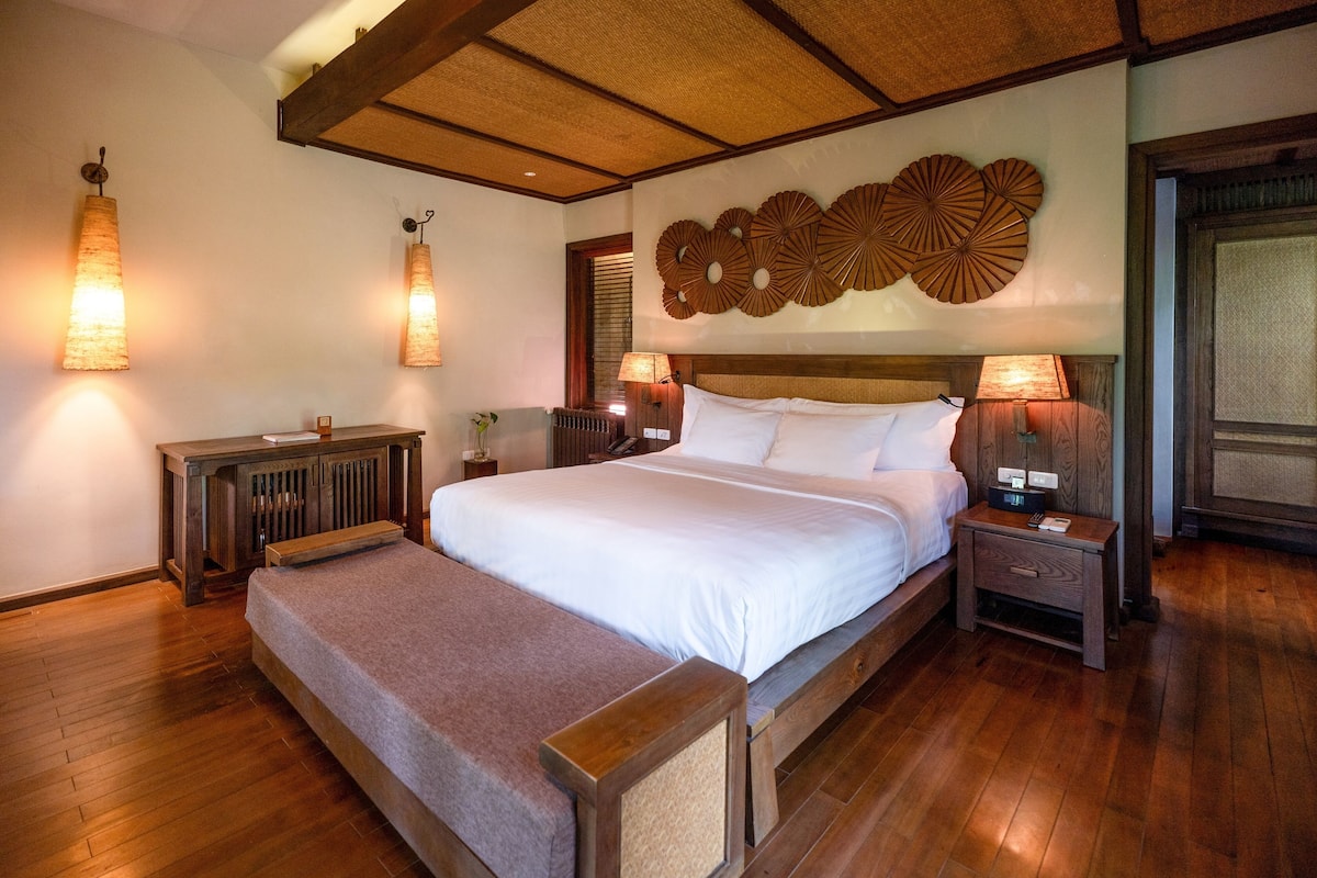 Une chambre spacieuse avec un grand lit, une tête de lit en bois et des lampes de chevet.