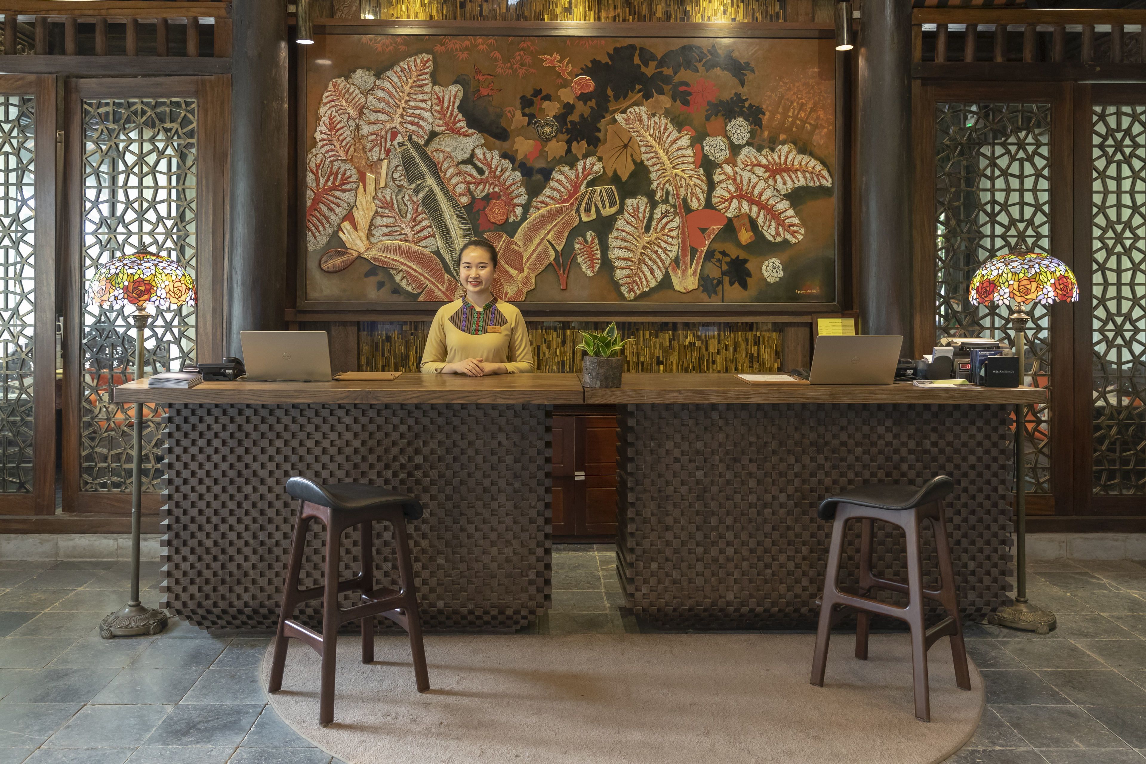 A reception desk with a large floral mural, two barstools, and a laptop on the counter.