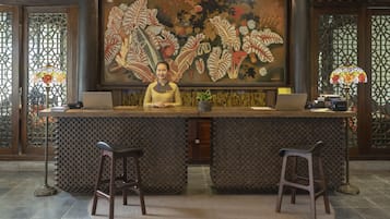 A reception desk with a large floral mural, two barstools, and a laptop on the counter.