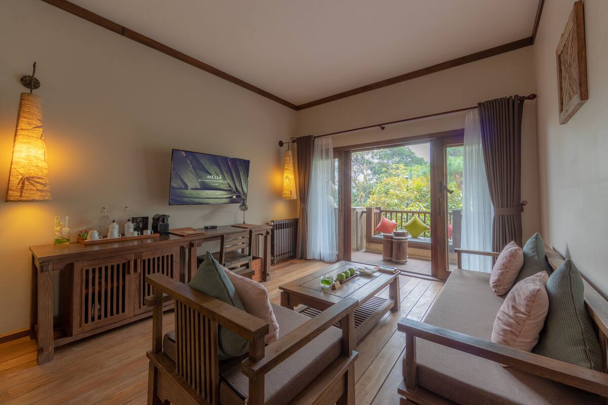 Un salon confortable, doté de meubles en bois, d’un téléviseur à écran plat et offrant une vue sur l’extérieur.