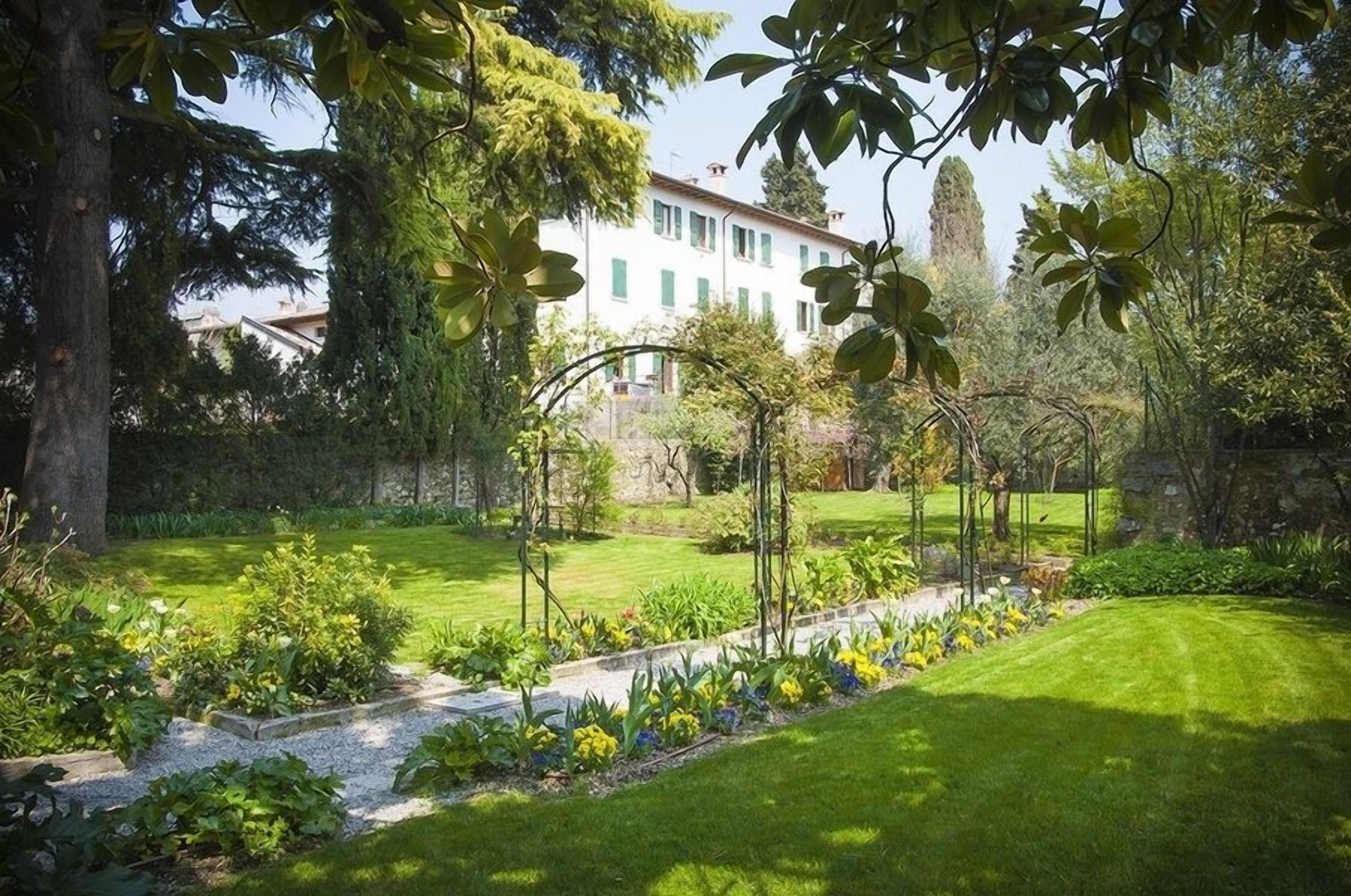 Ein gepflegter Garten mit Rasenfläche, unterschiedlichen Pflanzen und einem Kiesweg.