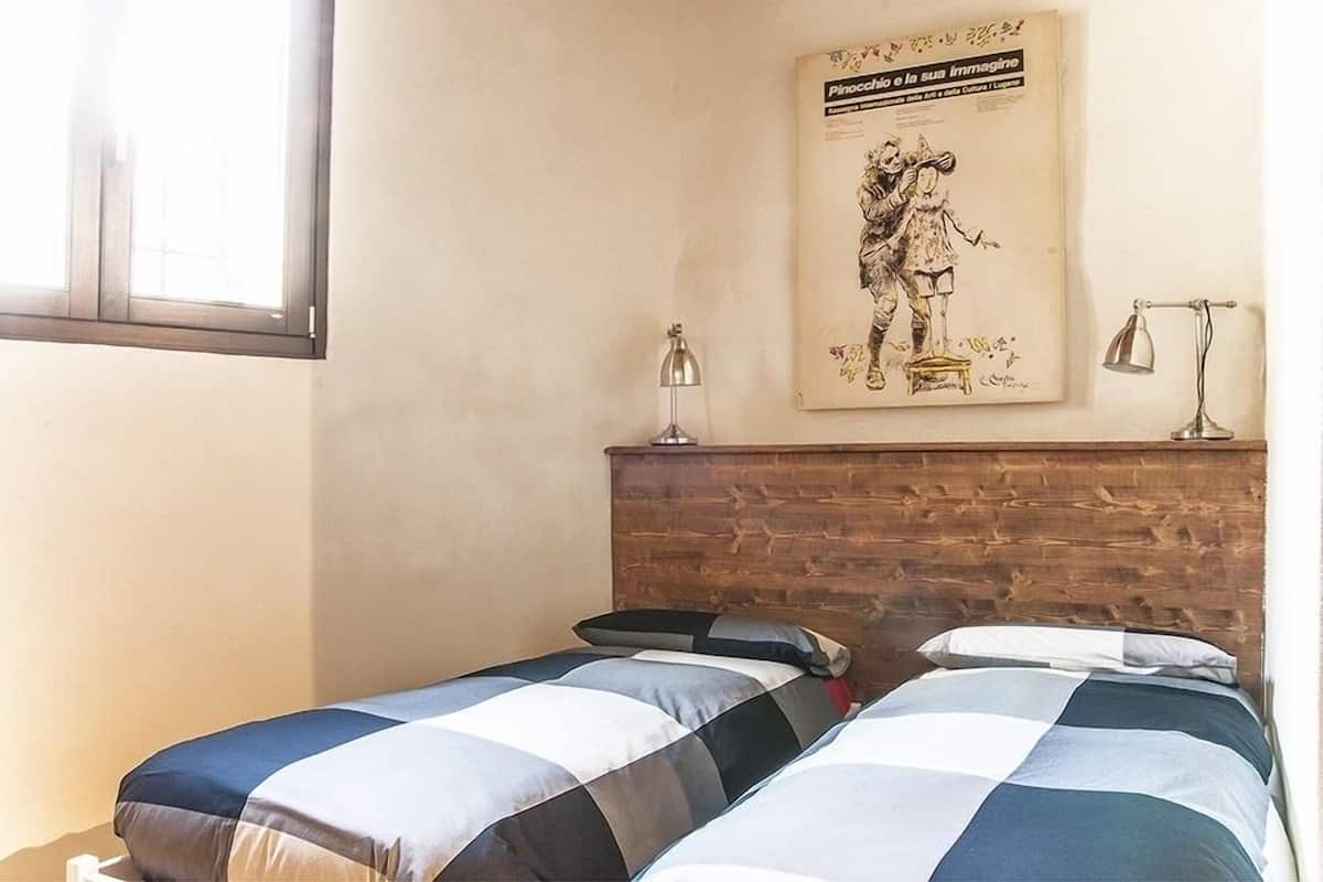 Een kamer met twee bedden, een houten hoofdbord, een wandlamp en een poster.