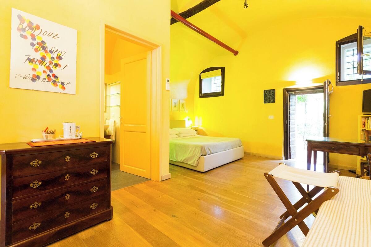 Een kamer met een bed, een houten dressoir, een klein tafeltje en een raam.