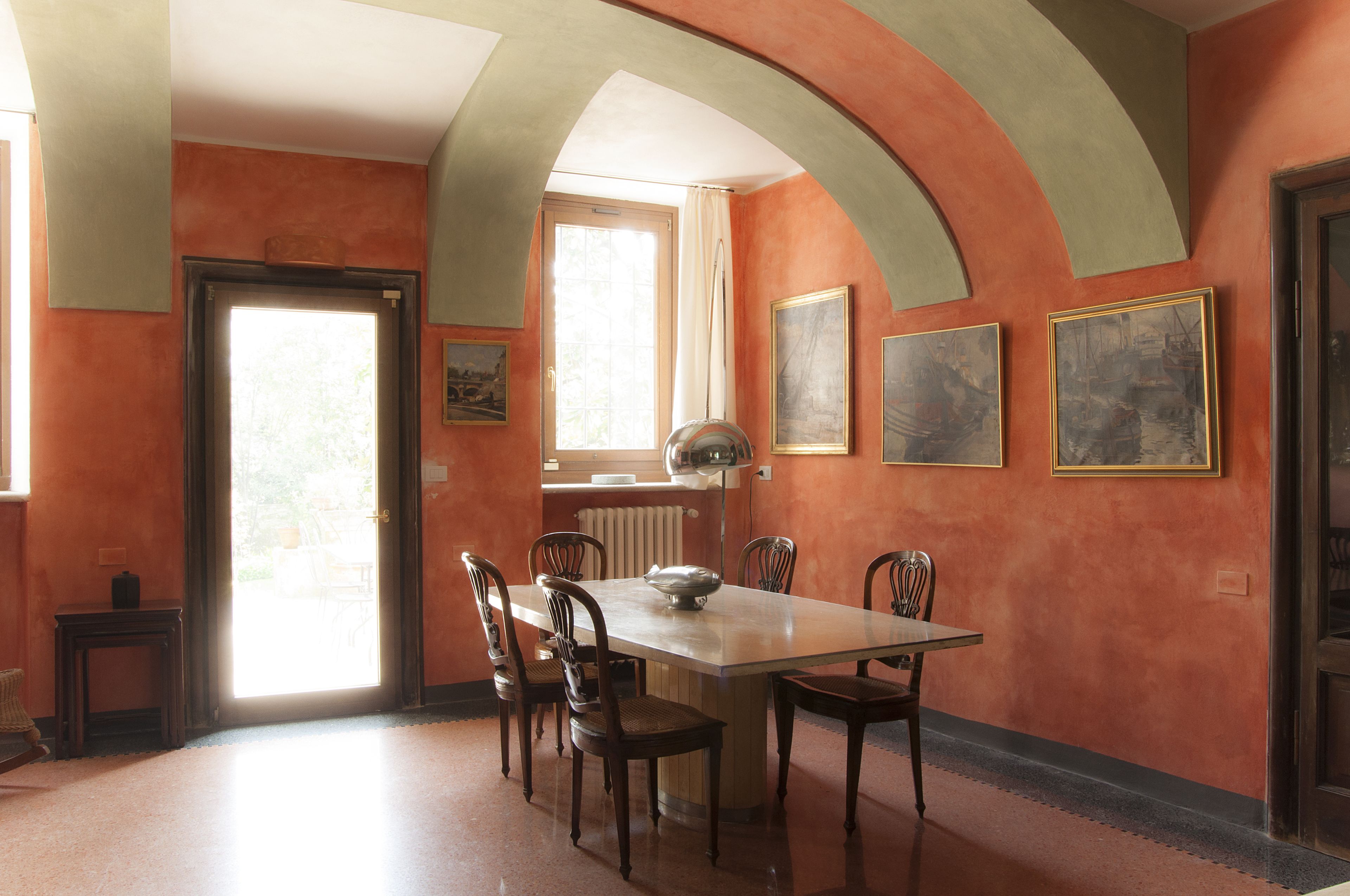 A dining area with a table and chairs, a radiator, and framed artwork on the walls.