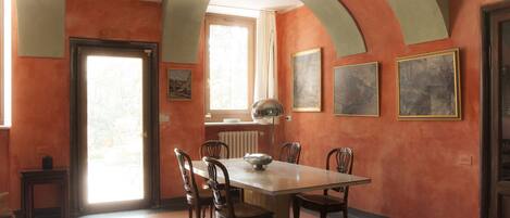A dining area with a table and chairs, a radiator, and framed artwork on the walls.