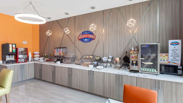 A breakfast counter with a sign reading "Raymont Breakfast Corner," equipped with various food items and appliances. - Baymont by Wyndham Houston Hobby Airport (Houston)
